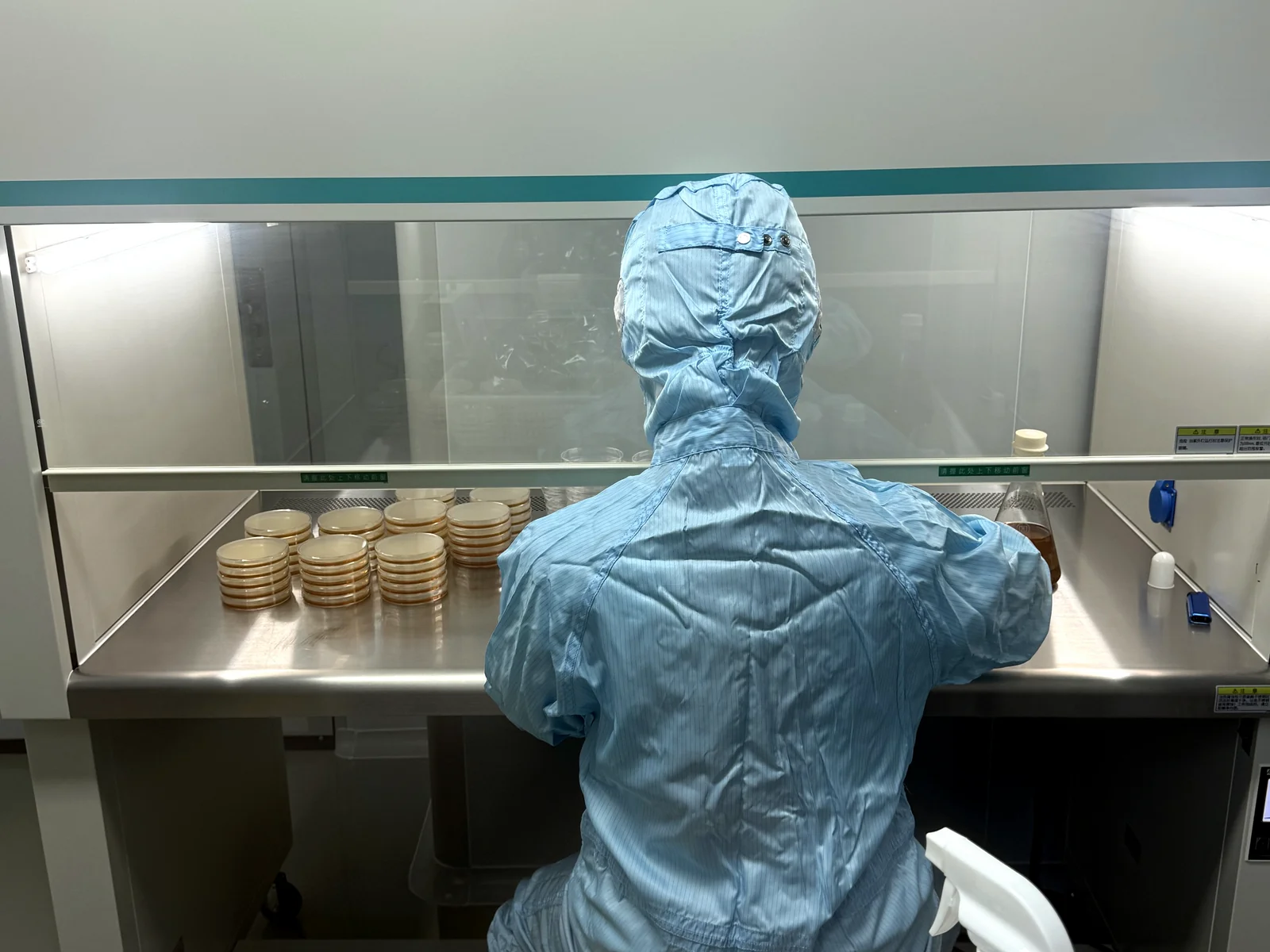 Cleanroom operator preparing culture plates for microbiological environmental monitoring at a supplier site.