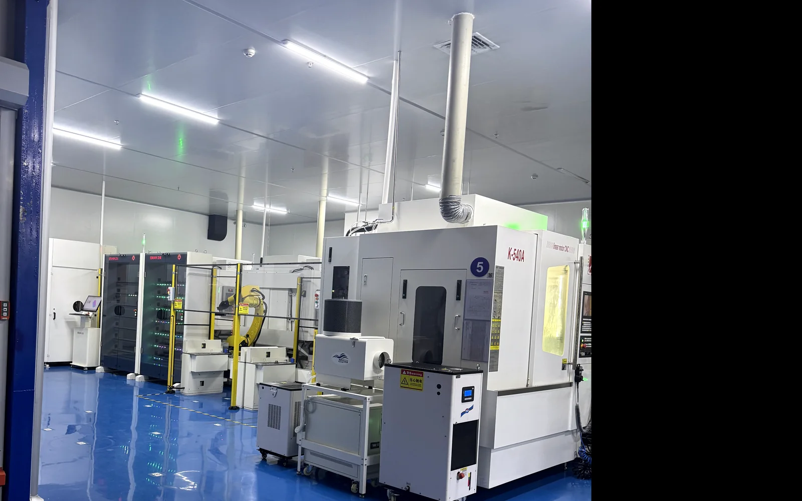 Automated manufacturing cell with a robotic arm in a controlled production area at a Chinese supplier.